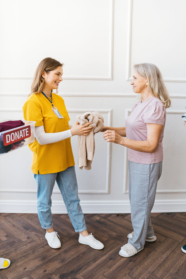 Elderly woman receiving adaptive clothing — caregiver handing a sweater