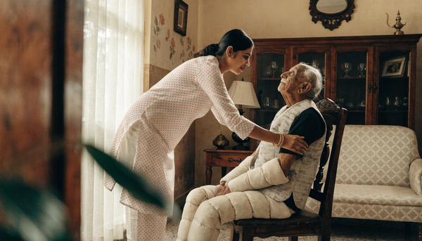 Indian family caregiver helping elderly patient in comfortable adaptive clothing for catheter home care