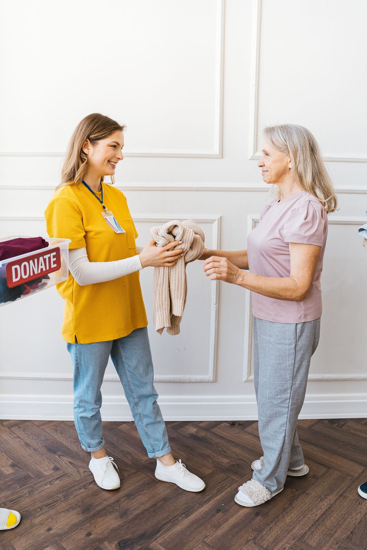 Elderly woman receiving adaptive clothing — caregiver handing a sweater